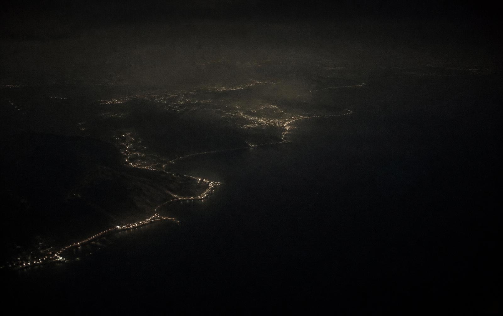 A dark coastline seen from altitude at night